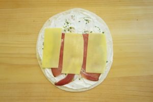 Premazati tortilje sirnim namazom, složiti pršut i sir